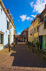 Traditional narrow cobblestone street with parked bicycles along vintage buildings in a residential district. Landscape photo of typical street in Utrecht. Selective focus. Tourism and travel concept
