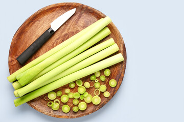 Board with slices of fresh leek on grey background