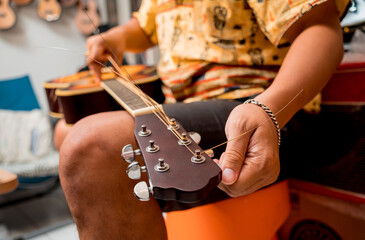 Young musician changing strings on a classical guitar in a guitar shop