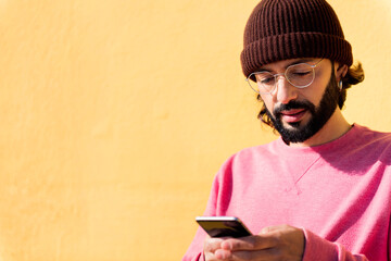 young man using mobile phone in a yellow background, concept of technology of communication and modern lifestyle, copy space for text
