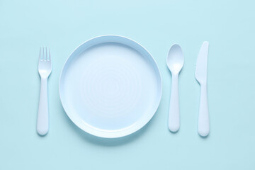 Plate with cutlery for baby on blue background