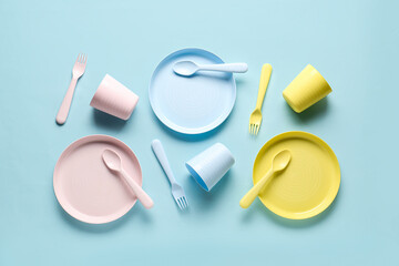 Plates with cups and cutlery for baby on blue background