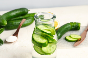 Bottle of infused water with cucumber slices on white table