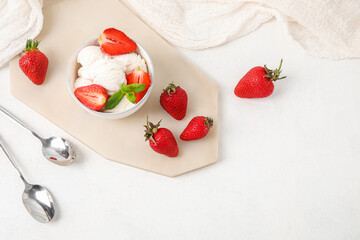 Fototapeta na wymiar Bowl of vanilla ice cream with strawberries, mint and spoons on white table