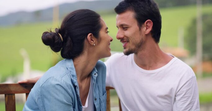 Young couple, kissing and relax on park bench with love, care and happiness for holiday, nature and outdoor together. Man, woman and kiss on forehead with bond, romance and freedom in spring for date