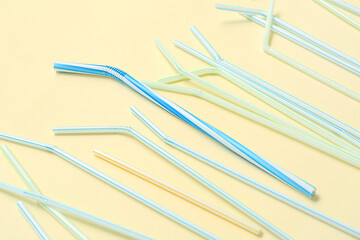 Different plastic drinking straws on beige background