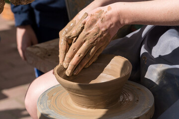Close up shot of hands making clay bowl during pottery lessons.