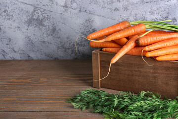 Box with fresh carrots on wooden table