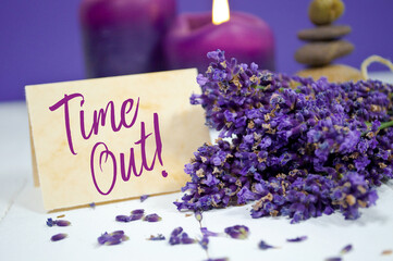 Slate chalk board and paper card board showing the word time out with lavender, stones and candles in the background
