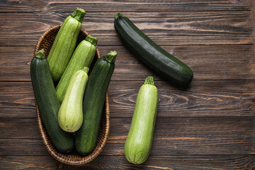 Wicker bowl with fresh green zucchini on wooden background
