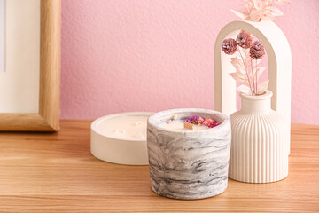 Holders with candles and decor on table near pink wall in room, closeup