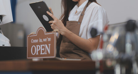 Welcome. Open. barista, waitress woman turning open sign board on glass door in modern cafe coffee shop ready to service, cafe restaurant, retail store, small business owner, food and drink concept
