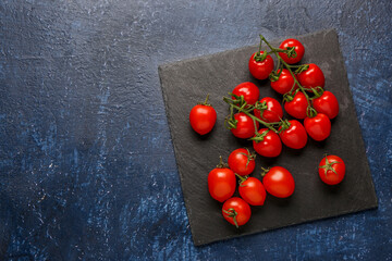 Board with fresh cherry tomatoes on blue background