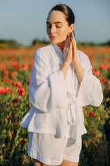 Young woman walking on meadow and enjoying by flowering poppies.