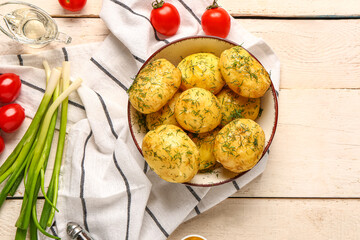 Plate of boiled baby potatoes with dill and tomatoes on white wooden background