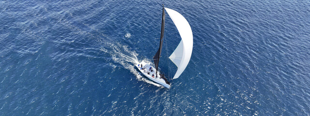 Aerial drone ultra wide photo of beautiful sailing boat with white sails cruising deep blue Aegean...