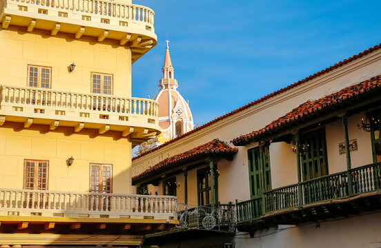 View to historic buildings with balconies, cathedral spire in the back against blue sky, Old Town Cartagena, Colombia