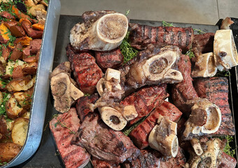 Pieces of meat and ribs cooked on grill. Food laid out on large plates for guests, invited to celebration. Meat dishes are very popular food.