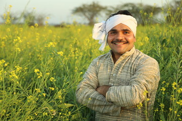 Happy Indian farmers standing in the mustard field and enjoying the benefits from the flourished...