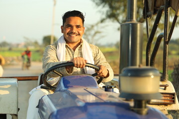 Happy Indian villager farmer sitting on the tractor enjoying the village life.