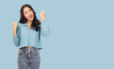 Excited young asian female with raised hands celebrating success Portrait cheerful positive asian woman with raised hands and fists open mouth Girl get happy Pastel blue background, copy space