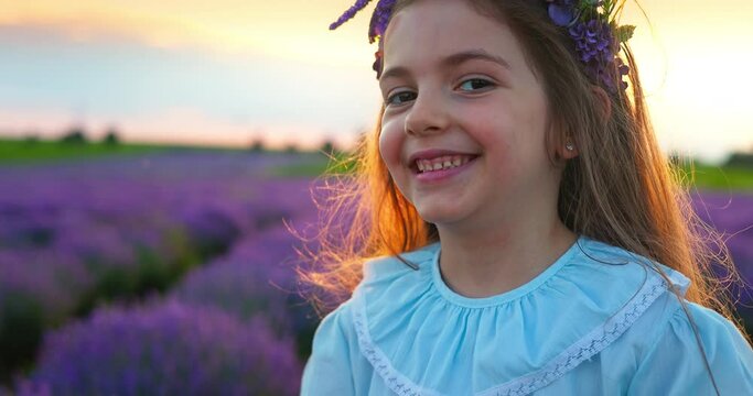 Happy carefree little girl with beautiful dress running in lavender field rows at sunset