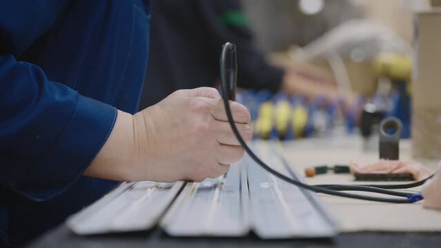Soldering a luminaire in an industrial lighting factory. In the frame are hands with a soldering iron and a diode tape.