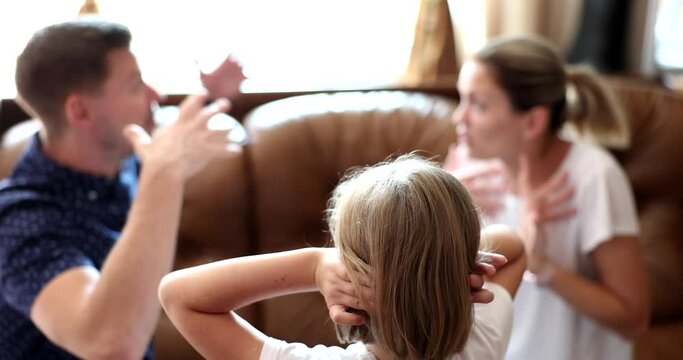 Rear view of child girl covers ears with hands while parents are quarreling. Child suffering from parental quarrels neglect or divorce