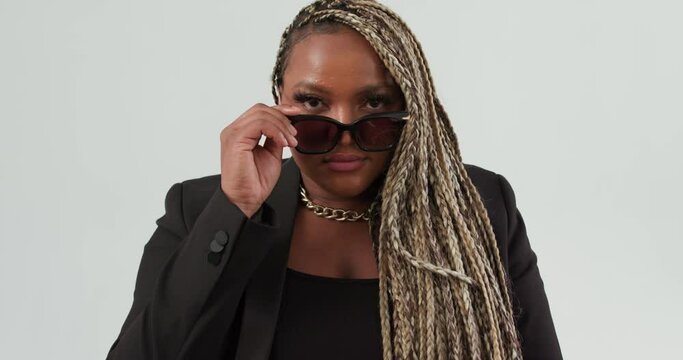 happy smiling Glamorous beautiful elegant African American model woman with dreadlocks in a fashionable black suit looking through sunglasses blinking winking eyes business flirt lifestyle