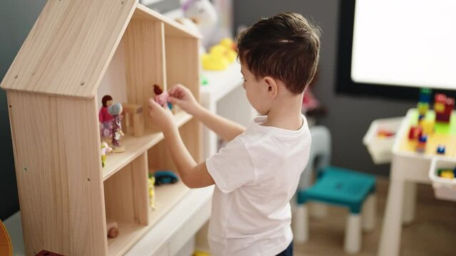 Adorable caucasian boy playing toy standing at kindergarten