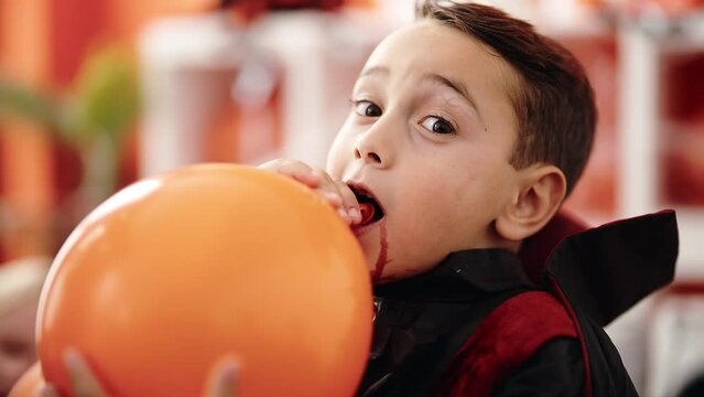 Adorable hispanic boy wearing halloween costume inflating balloon at home