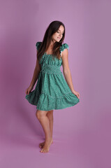 mulher sorridente com vestido verde em fundo rosa 