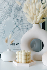 Creative composition of living room interior with copy space, stylish vase, wall with stucco.Home decor. Template. Hygge scene with candles on white background. Bunny candle. Bubbles candle