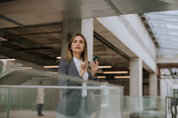 Young business woman using mobile phone in the office hallway