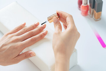 Obraz na płótnie Canvas A woman applying nail polish to her nails in her room. Nail care.