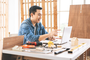 Middle age adult asian man carpenter using laptop for online working with customer wotk at home