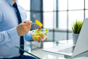 Unrecognizable businessman eating a vegetables salad for lunch, healthy and lifestyle concept.