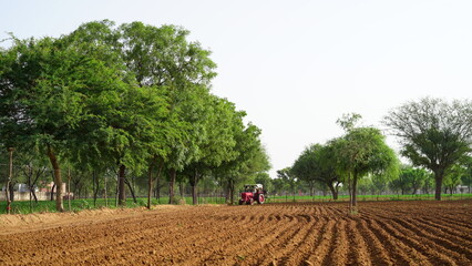 Farmer in tractor preparing land with seedbed cultivator as part of pre seeding activities in early spring season of agricultural works at farmlands.
