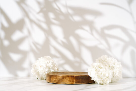 Cosmetics skin care product presentation display made with wooden podium and blossom branch on leaves shadow background. Studio photography.