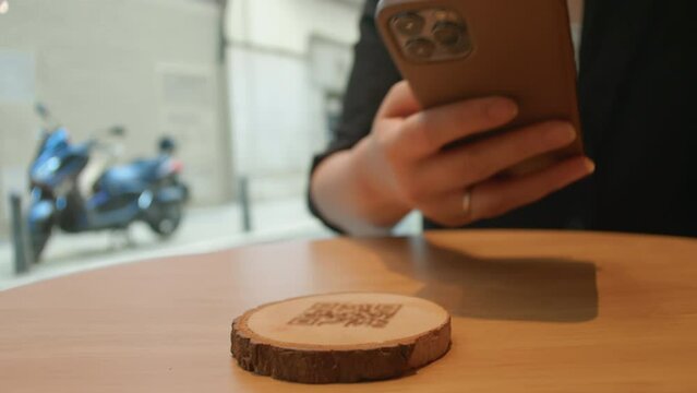Woman scans a QR code on her mobile phone at a cafe table