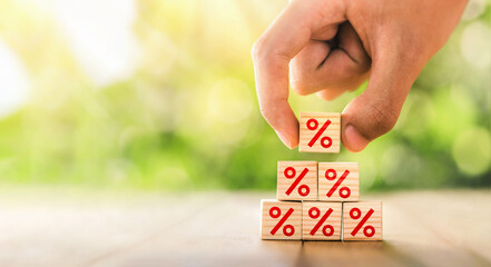 Interest rate financial and mortgage rates concept. Hand putting wood cube block increasing on top...