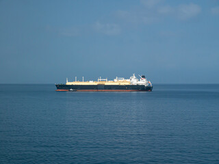 LNG Tanker with black hull and white deck structure drifting in the sea