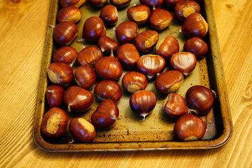 uncooked chestnuts on a metal baking tray