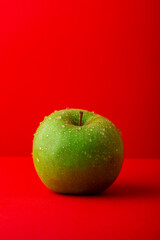 Manzana verde sobre fondo rojo formato horizontal