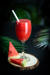 Watermelon juice isolated on dark background with green leaves