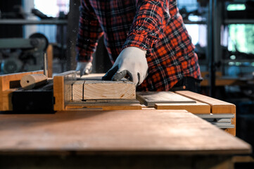 Carpenter working with machine electronic table circular saw for cutting plank wood in the...