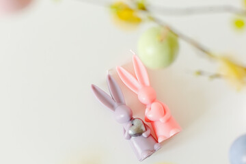 Congratulatory easter background. Easter eggs and flowers. Composition. Easter party concept. Photo of easter bunny ears white pink blue and yellow eggs on light background with copyspace. 