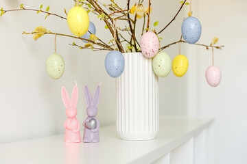 Congratulatory easter background. Easter eggs and flowers. Composition. Easter party concept. Photo of easter bunny ears white pink blue and yellow eggs on light background with copyspace. 