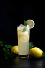 Cool freshly made lemonade and lemon fruits on black background. Space for text. AI generated