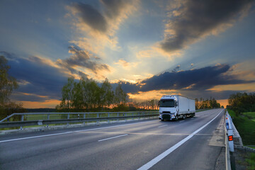 Fototapeta na wymiar Cargo truck driving through landscape at sunset
